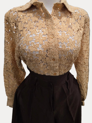A tan lace long-sleeve blouse displayed on a mannequin torso, paired with dark brown high-waisted pants in a kitchen setting.