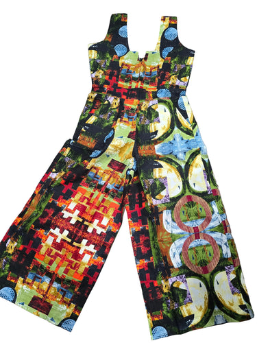 A sleeveless wide-leg jumpsuit with a highly colorful, abstract geometric and organic print, laid flat on a dark wood floor.