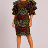 A woman modeling a knee-length bodycon dress with dramatic ruffled short sleeves. The dress features a bold, multicolored spiral rose pattern in red, yellow, green, and black.