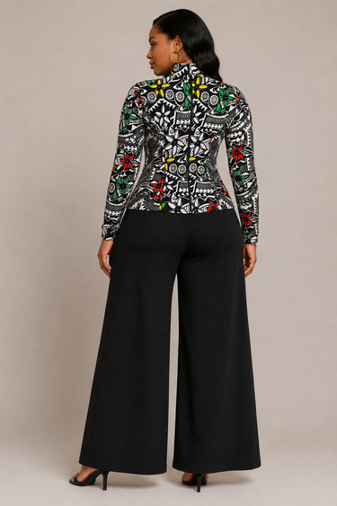 A woman shown from the back wearing a long-sleeve mock-neck top with a black, white, green, and red graphic pattern, paired with wide-leg black pants and black heels, against a solid beige studio background.
