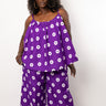 A woman modeling a matching purple two-piece lounge set with a white circular dot pattern, featuring a sleeveless top and wide-leg pants, against a plain white background.